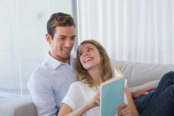 Young couple reading book on couch — Stock Photo, Image