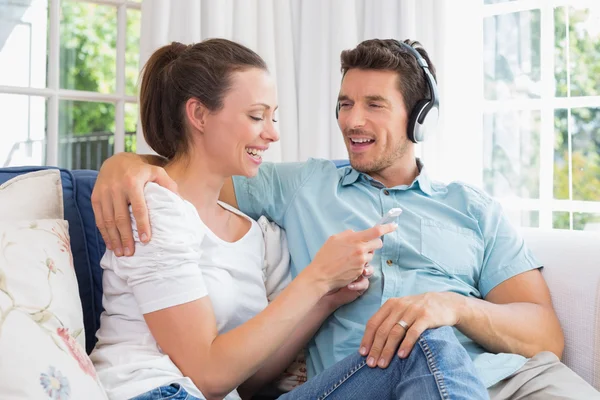 Pareja escuchando música con teléfono móvil en el sofá —  Fotos de Stock