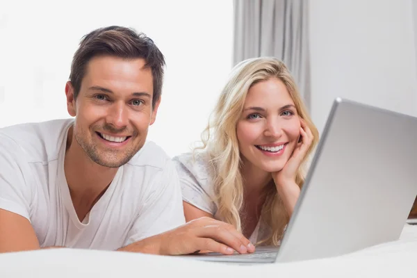 Relaxed young couple using laptop in bed — Stock Photo, Image
