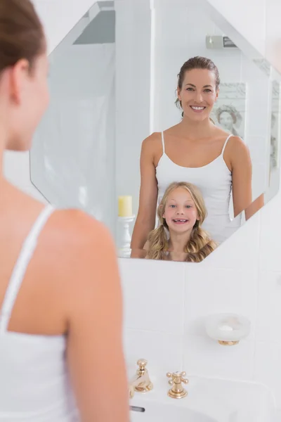 Happy mother and daughter looking at bathroom mirror — Stock Photo, Image