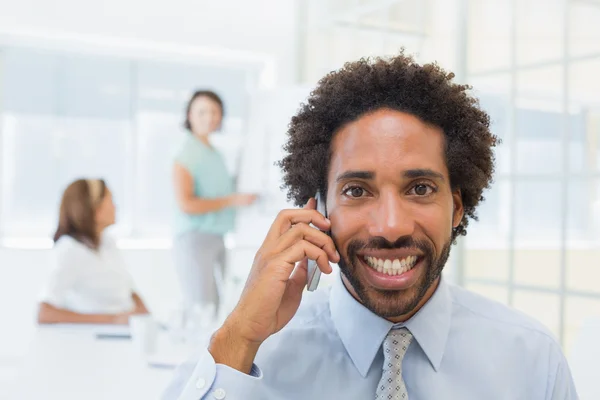 Smiling businessman on call with colleagues at office — Stock Photo, Image