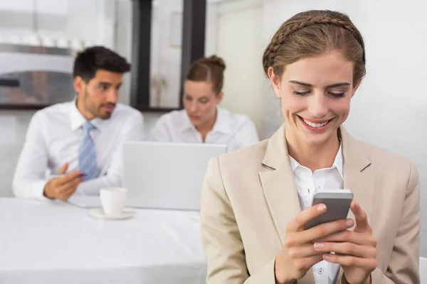 Affärskvinna textmeddelanden med kollegor på skrivbord — Stockfoto