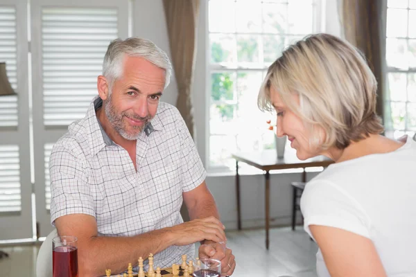 Счастливая взрослая пара играет в шахматы дома — стоковое фото