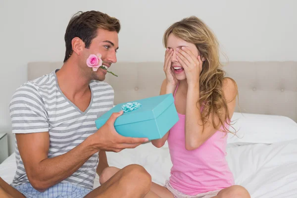 Man surprising woman with a gift box in bed — Stock Photo, Image