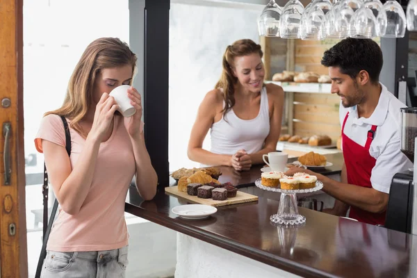 Woman drinking coffee with friend and male barista in coffee shop — Stock Photo, Image