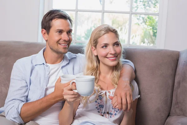 Relaxado casal amoroso com xícaras de café na sala de estar — Fotografia de Stock