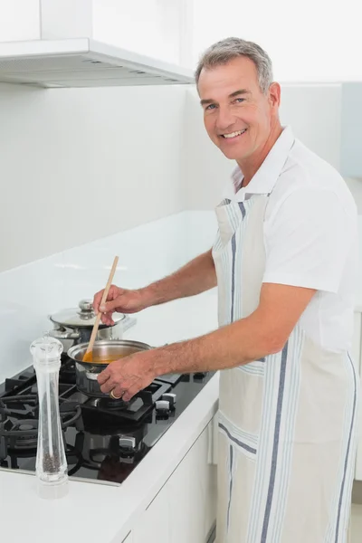 Retrato de um homem sorridente preparando comida na cozinha — Fotografia de Stock