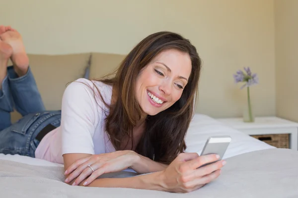 Genç kadın kısa mesaj yatakta gülümseyen — Stok fotoğraf