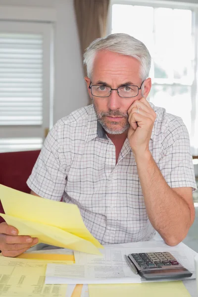 Серьезный взрослый человек с домашними счетами и калькулятором — стоковое фото