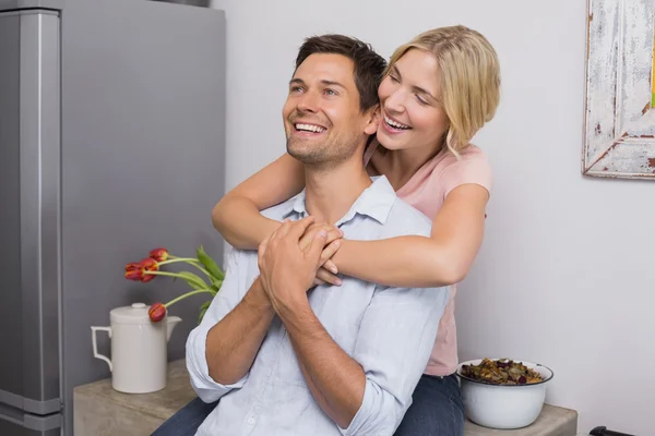 Cheerful woman embracing man from behind at home — Stock Photo, Image