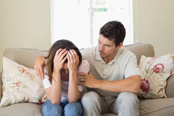 Homem consolando uma mulher triste na sala de estar — Fotografia de Stock