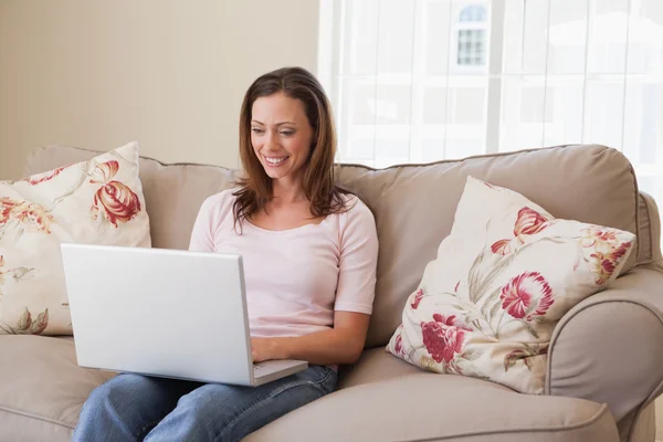 Leende kvinna med laptop i vardagsrum — Stockfoto