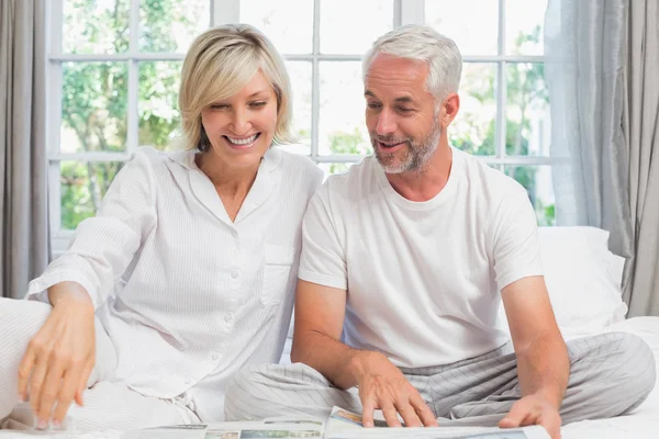 Smiling mature couple sitting on bed at home — Stock Photo, Image
