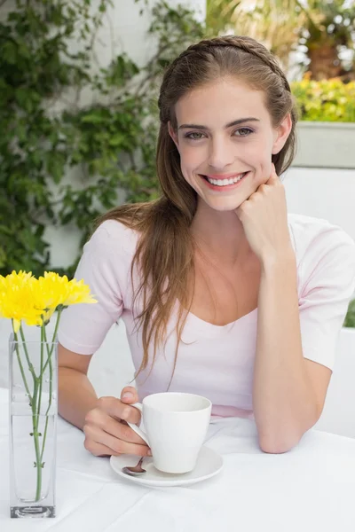 Mujer joven sonriente con taza de café en la cafetería —  Fotos de Stock