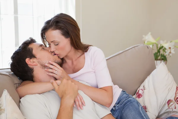 Любящая молодая пара целуется на диване — стоковое фото