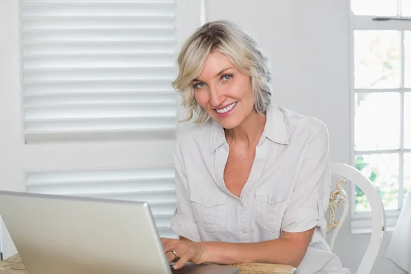 Lachende volwassen vrouw met laptop thuis — Stockfoto