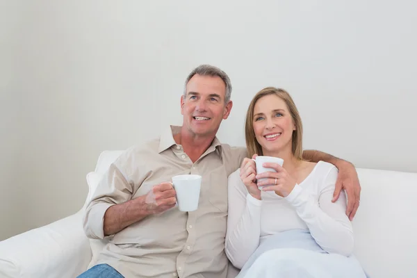 Liefdevol paar met koffie cups weg op zoek in woonkamer — Stockfoto