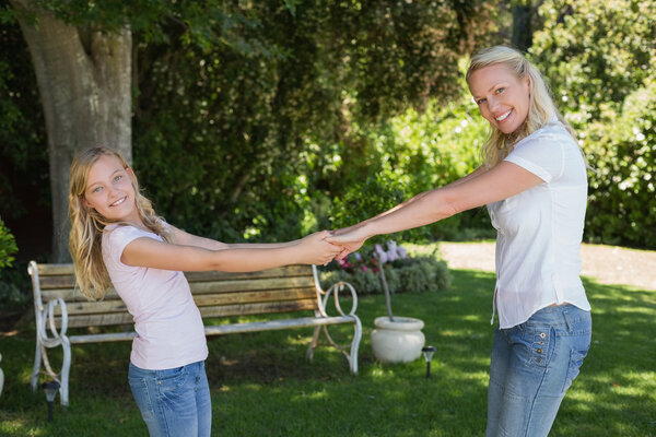 Happy mother and daughter holding hands in park Stock Photo