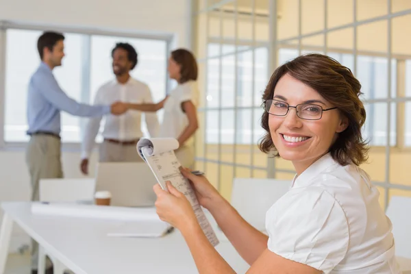 Glimlachende zakenvrouw met collega's handen schudden op achtergrond Stockafbeelding