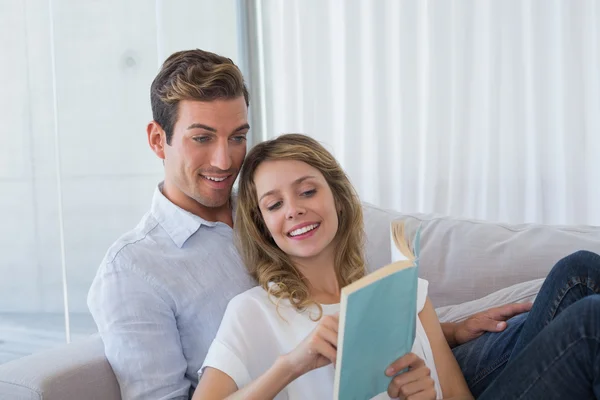 Junges Paar liest Buch auf Couch lizenzfreie Stockfotos