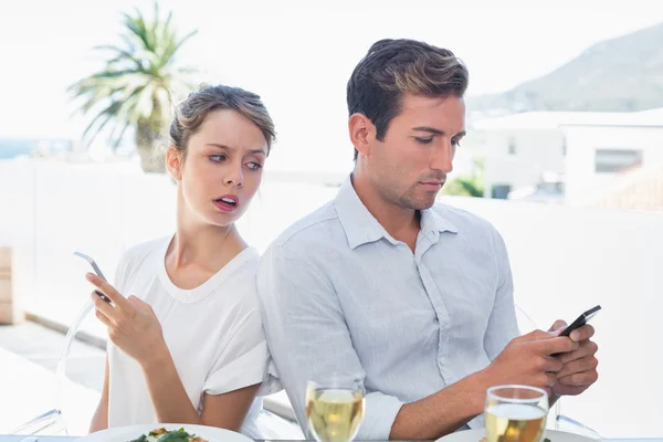 Couple text messaging at food table Stock Picture