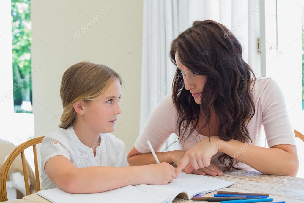 Woman helping daughter in homework at table