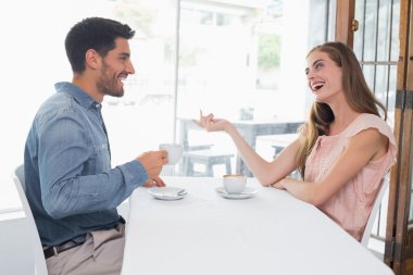 Kahve dükkanında gülümseyen bir çift yan görünüm