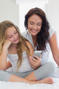 Anne ve kızı yatakta istimal hareket eden telefon