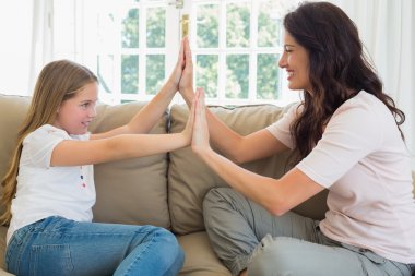 Anne ve kızı koltukta beraber elleri ile