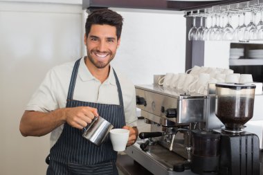 Waiter smiling and making cup of coffee at coffee shop clipart