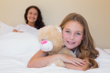 küçük kız anne arka planda da oyuncak ayı kucaklayan