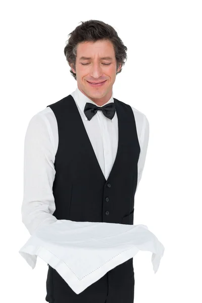 Smiling waiter looking at tray over white background — Stock Photo, Image