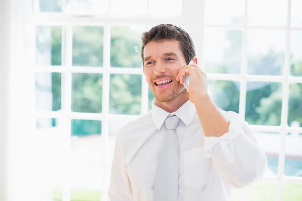 Lachende zakenman met behulp van mobiele telefoon thuis — Stockfoto