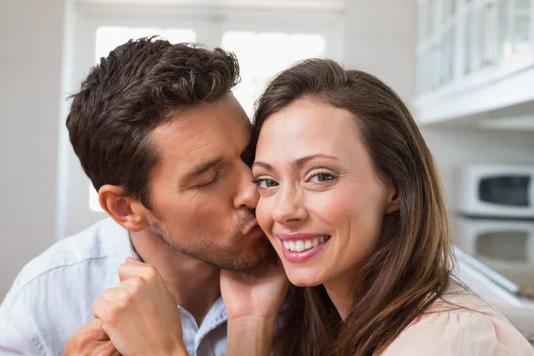 Homem amoroso beijando mulher na bochecha em casa — Fotografia de Stock