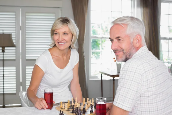 Mature couple looking away while playing chess — Stock Photo, Image