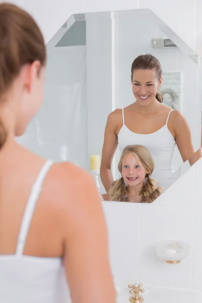 Happy mother and daughter looking at bathroom mirror — Stock Photo, Image