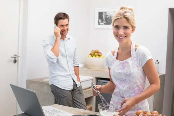 Woman preparing cookies while man on call in kitchen — Stock Photo, Image