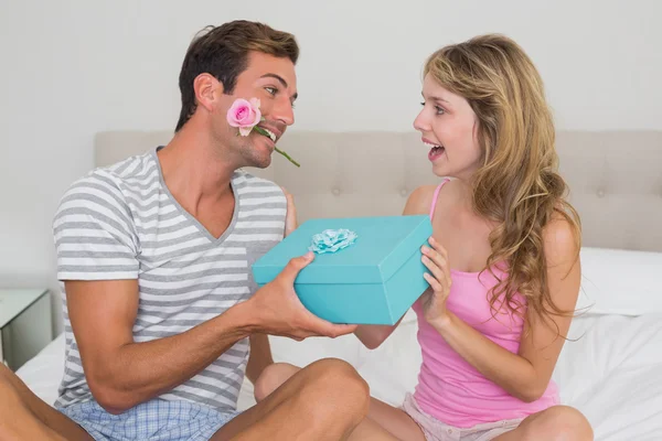 Homme donnant femme heureuse une boîte cadeau dans le lit — Photo