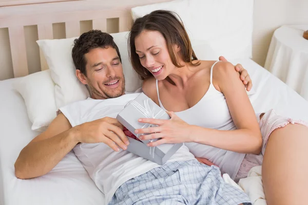 Paar mit Geschenkbox liegt zusammen im Bett — Stockfoto