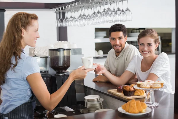 Female waiter giving coffee to a couple at coffee shop — Stock Photo, Image