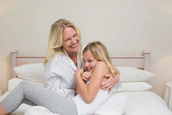 Mujer cosquillas hija en la cama — Foto de Stock