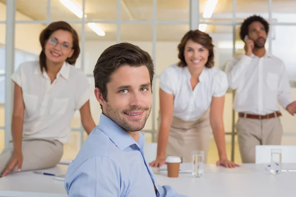 Lachende jonge zakenman met collega's op kantoor — Stockfoto