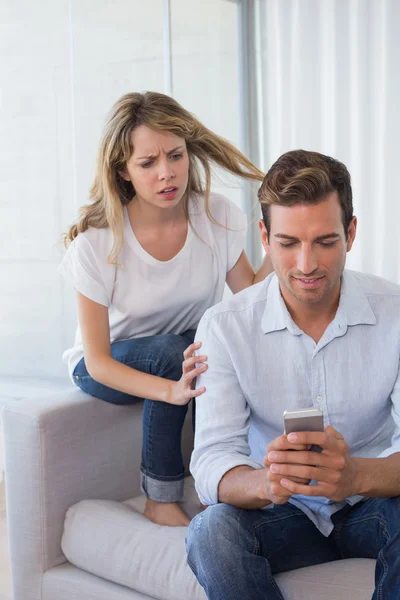 Mujer mirando mensajes de texto del hombre en la sala de estar — Foto de Stock
