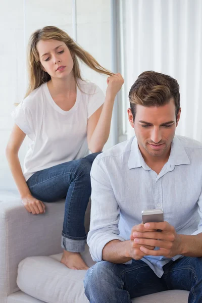 Mujer mirando mensajes de texto del hombre en la sala de estar —  Fotos de Stock