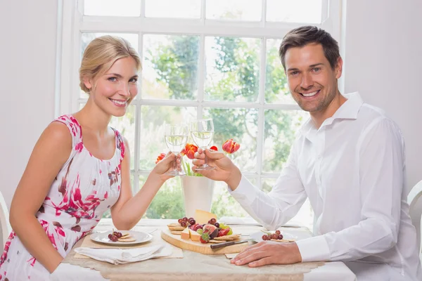 Glückliches junges Paar stößt mit Weingläsern auf Essen an — Stockfoto