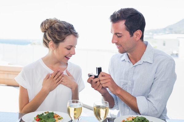 Man surprising woman with a wedding ring at lunch table