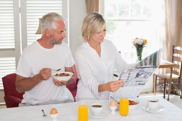 Couple reading newspaper while having breakfast — Stock Photo, Image