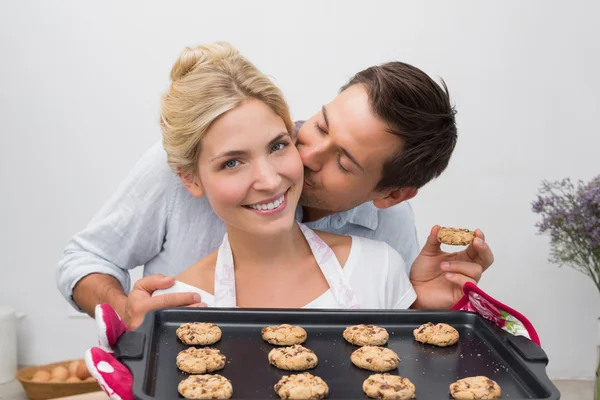 Uomo baciare guancia di donna come lei tiene biscotti appena sfornati — Foto Stock