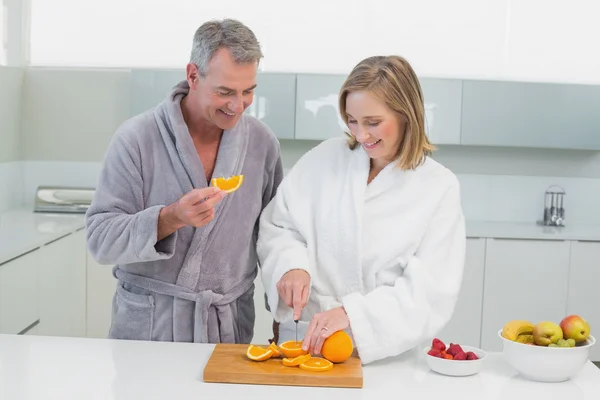 Casal feliz cortando laranja na cozinha — Fotografia de Stock