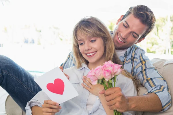 Casal com flores e cartão de saudação em casa — Fotografia de Stock